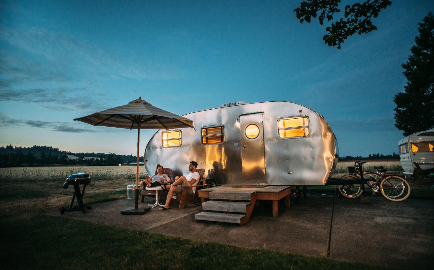 man and woman sitting in front of RV trailer by Blake Wisz courtesy of Unsplash.