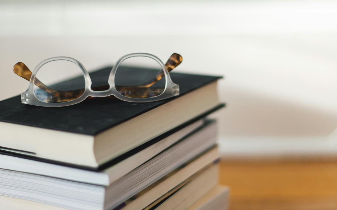 clear framed eyeglasses on top of pile of books by Kari Shea courtesy of Unsplash.