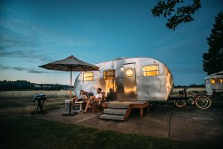 man and woman sitting in front of RV trailer by Blake Wisz courtesy of Unsplash.