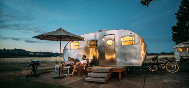man and woman sitting in front of RV trailer by Blake Wisz courtesy of Unsplash.