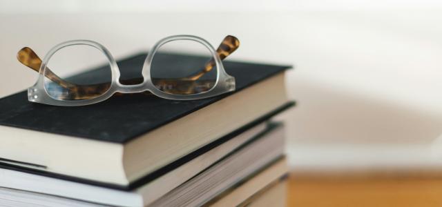 clear framed eyeglasses on top of pile of books by Kari Shea courtesy of Unsplash.