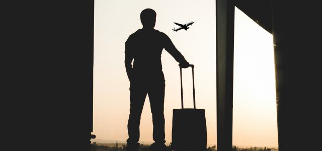 silhouette of man holding luggage inside airport by yousef alfuhigi courtesy of Unsplash.